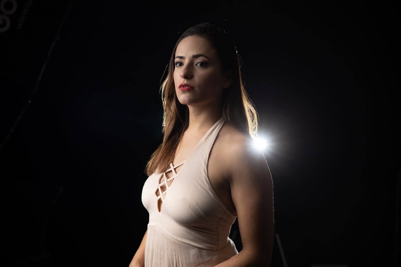 Woman in evening dress with dramatic lighting on a black background.